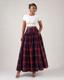 Woman wearing a white top and plaid skirt on a plain background