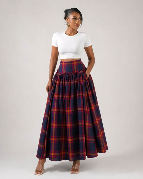 Woman wearing a white top and plaid skirt on a plain background